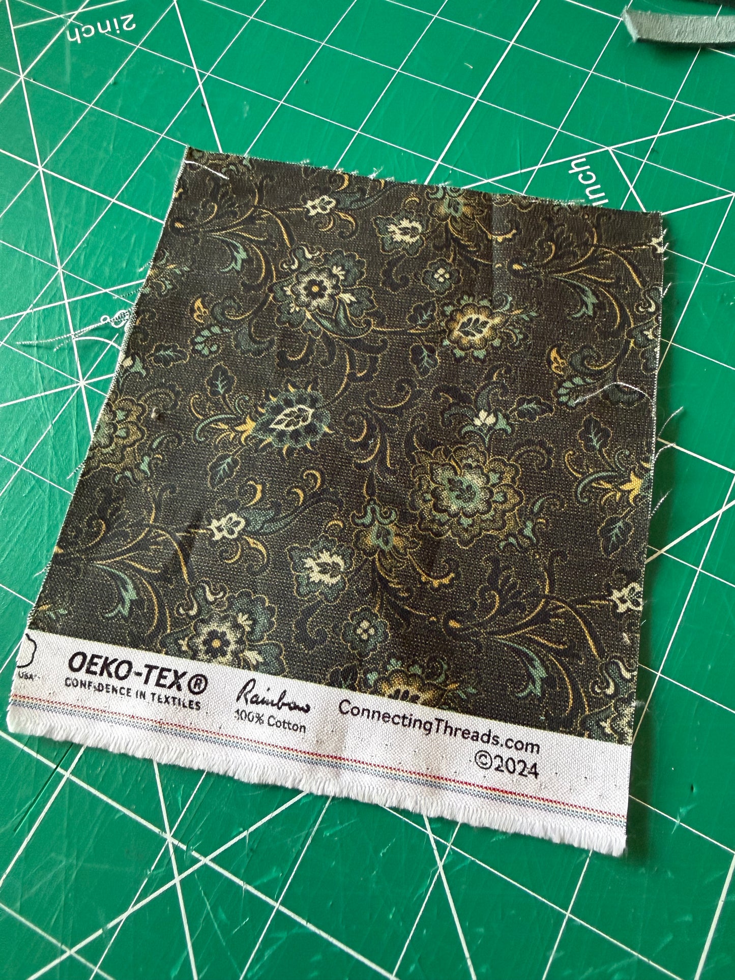 Fabric swatch with floral pattern on a green cutting mat